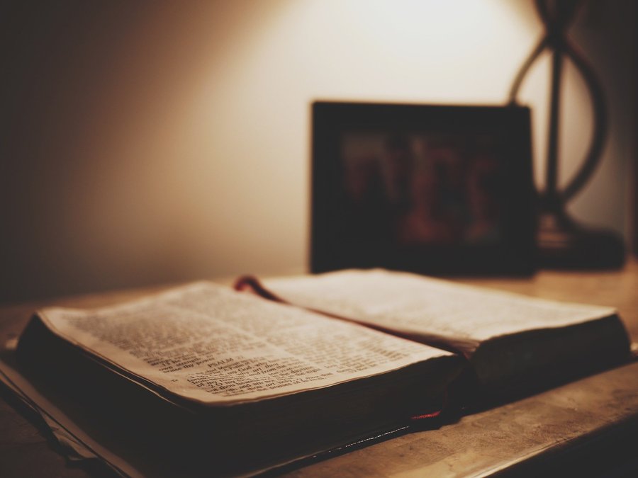 Aufgeschlagene Bibel auf einem Tisch im warmen Licht